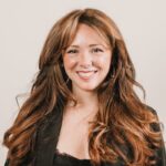 Elegant headshot of a smiling woman in a black blazer, showcasing confidence.